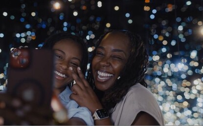 A mom and daughter smiling, taking a selfie inside Yayoi Kusama's Infinity Mirrored Room at The Broad