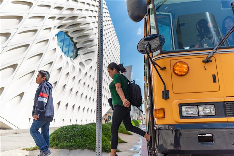 A children and adult stepping off of a school bus at The Broad